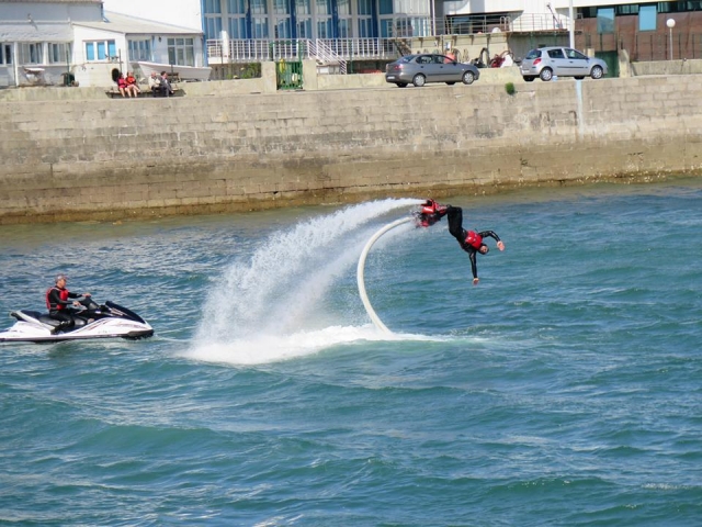hombre practicando acrobacia lateral con una moto de agua blanca al lado.jpg